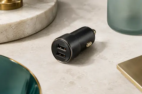Chargeur voiture compact en alliage d’aluminium noir avec deux ports USB sur une surface minérale claire