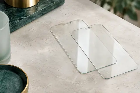 Deux protections d’écran transparentes en verre trempé, aux bords arrondis, posées sur une surface claire.