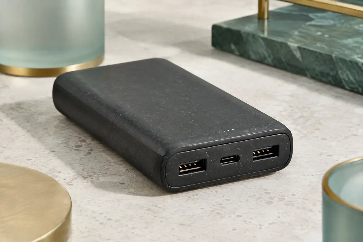Batterie externe noire Belkin BoostCharge avec ses ports USB-C et USB-A posée sur une surface minérale claire.