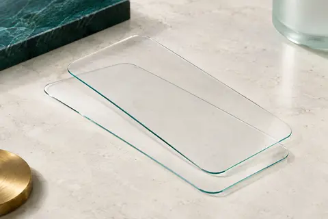 Deux films transparents en verre trempé aux bords arrondis présentés sur une surface minérale claire.