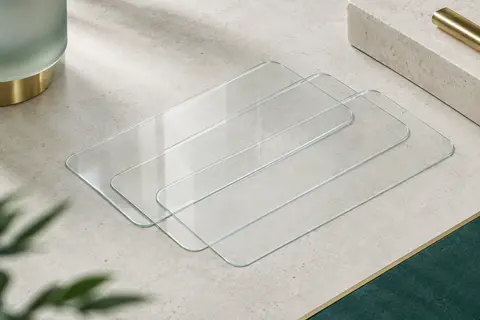 Lot de trois protections transparentes en verre trempé aux bords arrondis, posé sur une surface claire