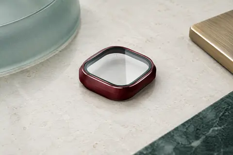 Protecteur d’objectifs en verre transparent avec cadre bordeaux et finition mate posé sur une surface claire