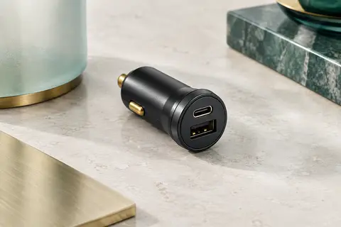 Chargeur voiture noir compact Iniu avec ports USB-C et USB-A visibles sur une surface minérale claire.