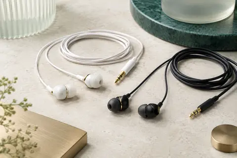 Deux paires d’écouteurs filaires intra-auriculaires, blanche et noire, avec microphone et prises jack visibles.