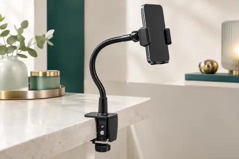 Support de téléphone noir à bras flexible fixé sur une surface claire, avec pince et tête orientable.