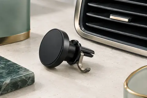 Support voiture magnétique noir à crochet métallique, présenté près d’une grille horizontale.