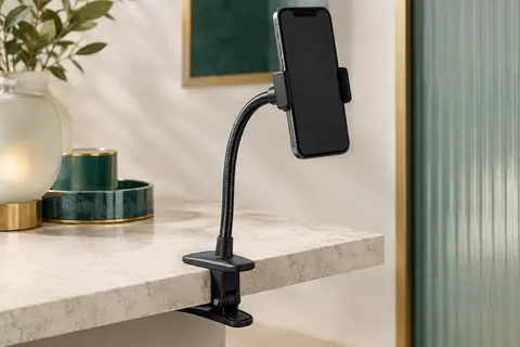 Support noir à bras flexible maintenant un smartphone sur le bord d’une surface claire