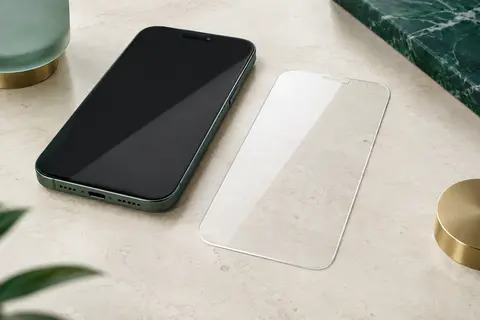 Verre trempé transparent aux bords arrondis posé près d’un smartphone sur une surface claire