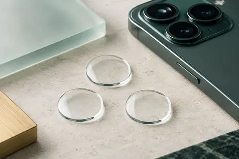 Trois protections transparentes en verre trempé pour objectifs arrière d’iPhone 12 sur une surface claire