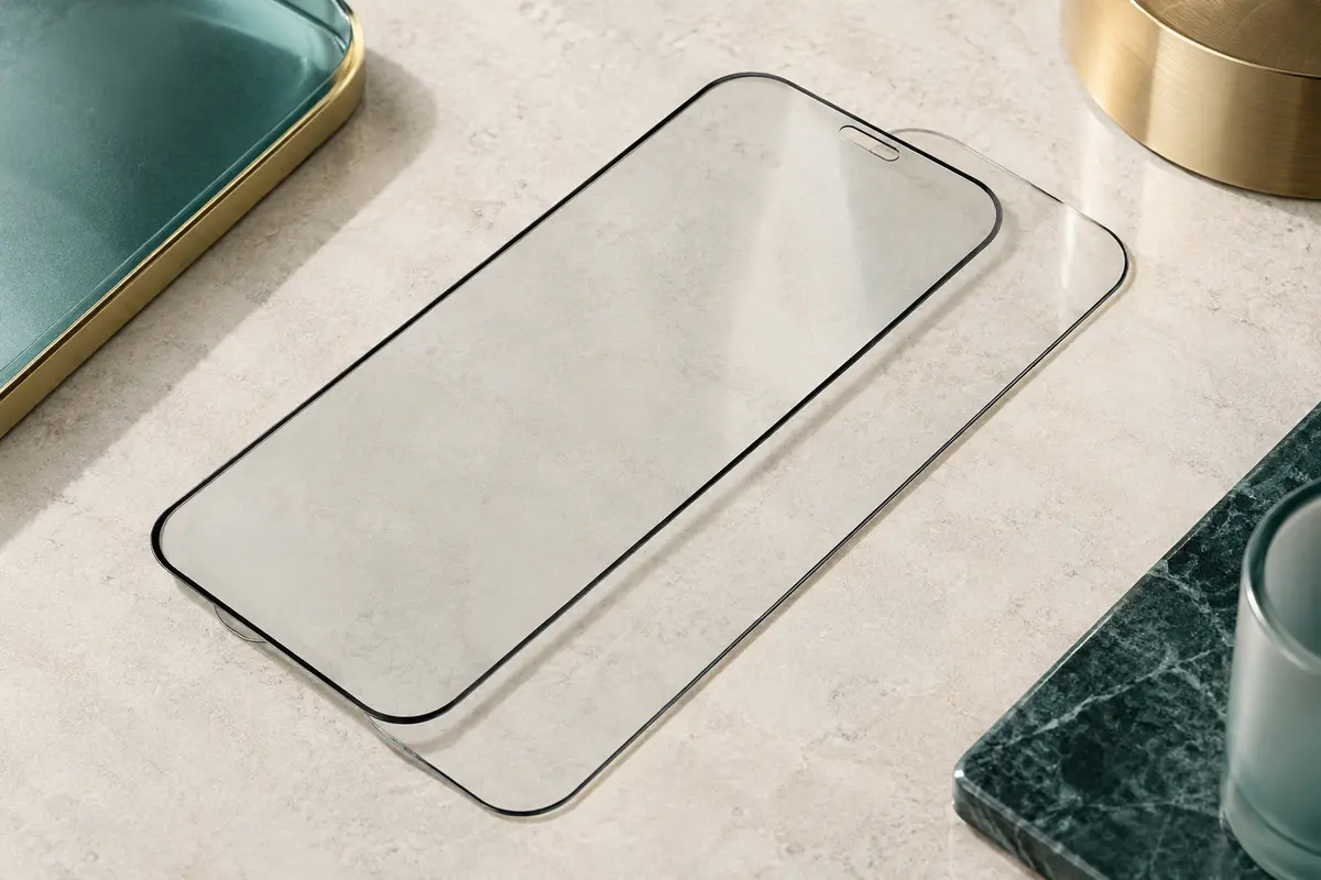 Deux protections d’écran en verre trempé transparent avec bords noirs sur une surface minérale claire