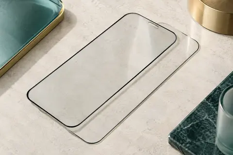 Deux protections d’écran en verre trempé transparent avec bords noirs sur une surface minérale claire